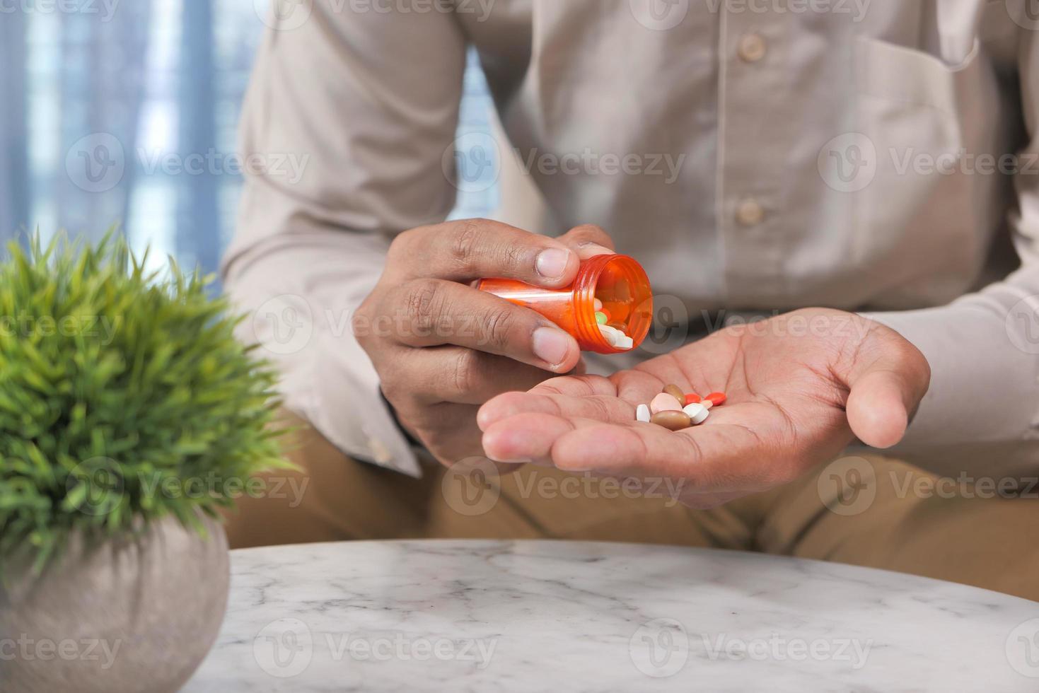 Mann, der Medikamente aus einer Tablettenfläschchen nimmt foto