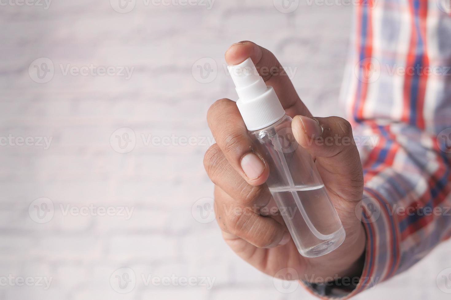 Nahaufnahme einer Hand eines jungen Mannes mit Händedesinfektionsspray foto