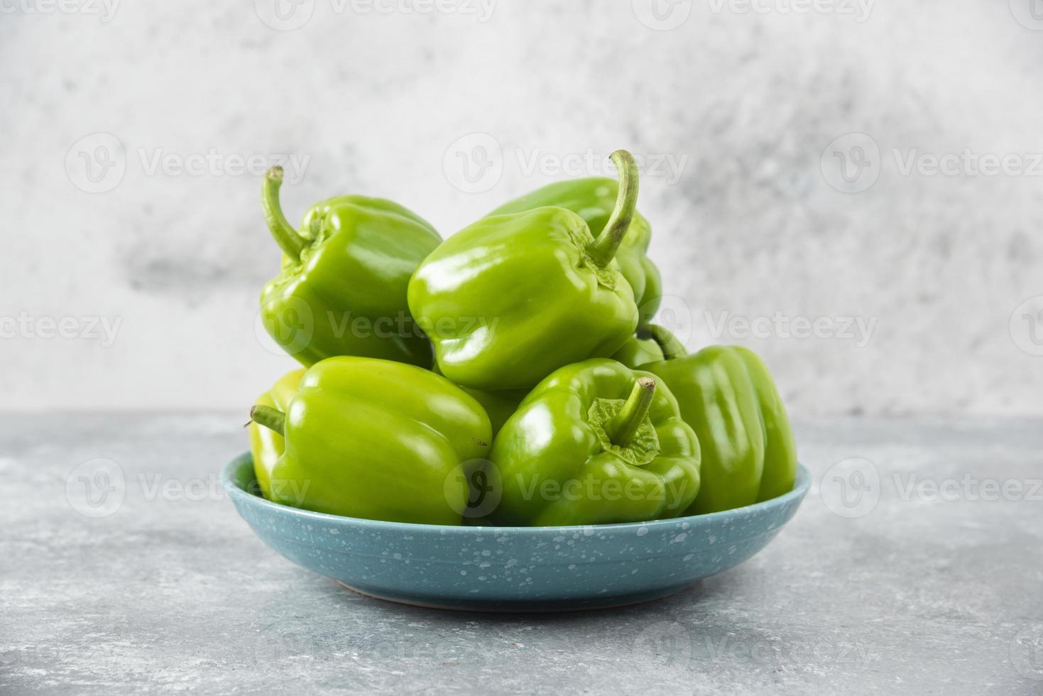 frische grüne Paprika auf einem blauen Teller auf einem Steintisch foto