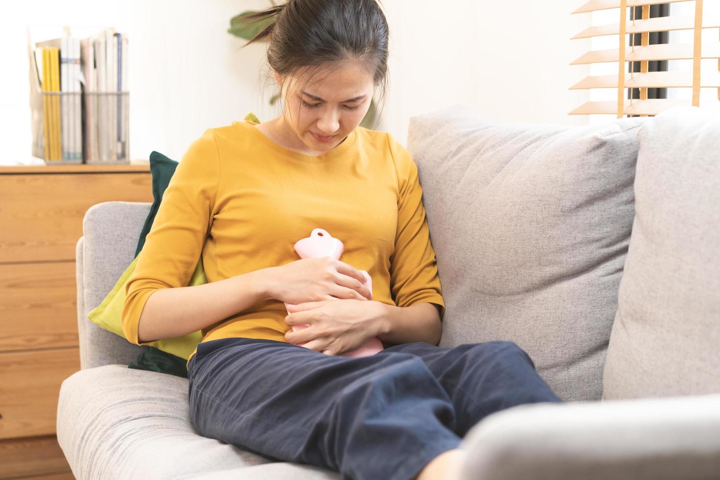 Menstruation, Zeitraum Zyklus von monatlich, verletzt asiatisch jung Frau, weiblich Hand im Magenschmerzen, leiden von prämenstruelle, Bauch oder Abdomen Schmerz, mit heiß Wasser Flasche. Gesundheit Problem Entzündung im Körper. foto