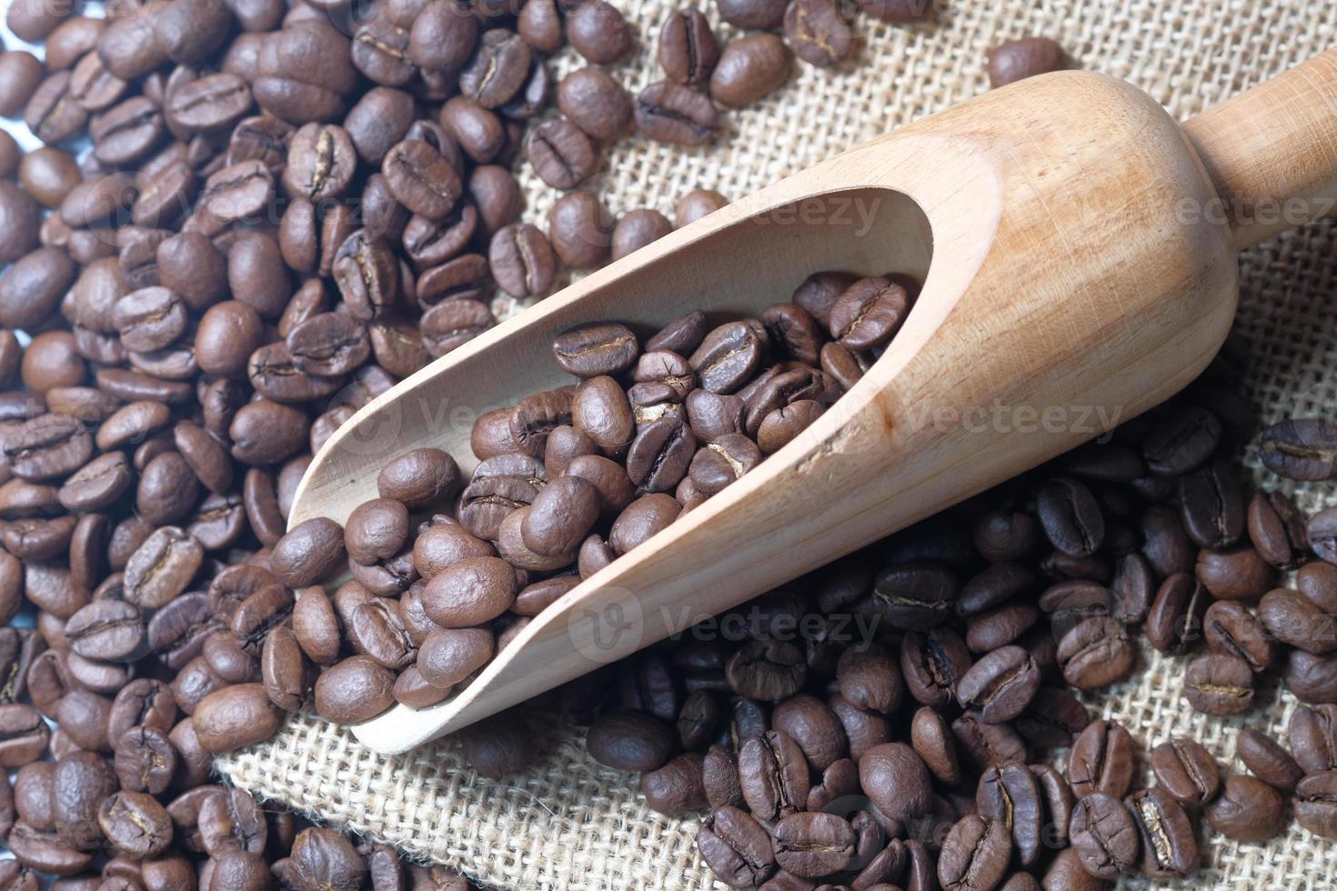 Draufsicht der frischen Kaffeebohnen im Holzlöffel auf Tisch foto