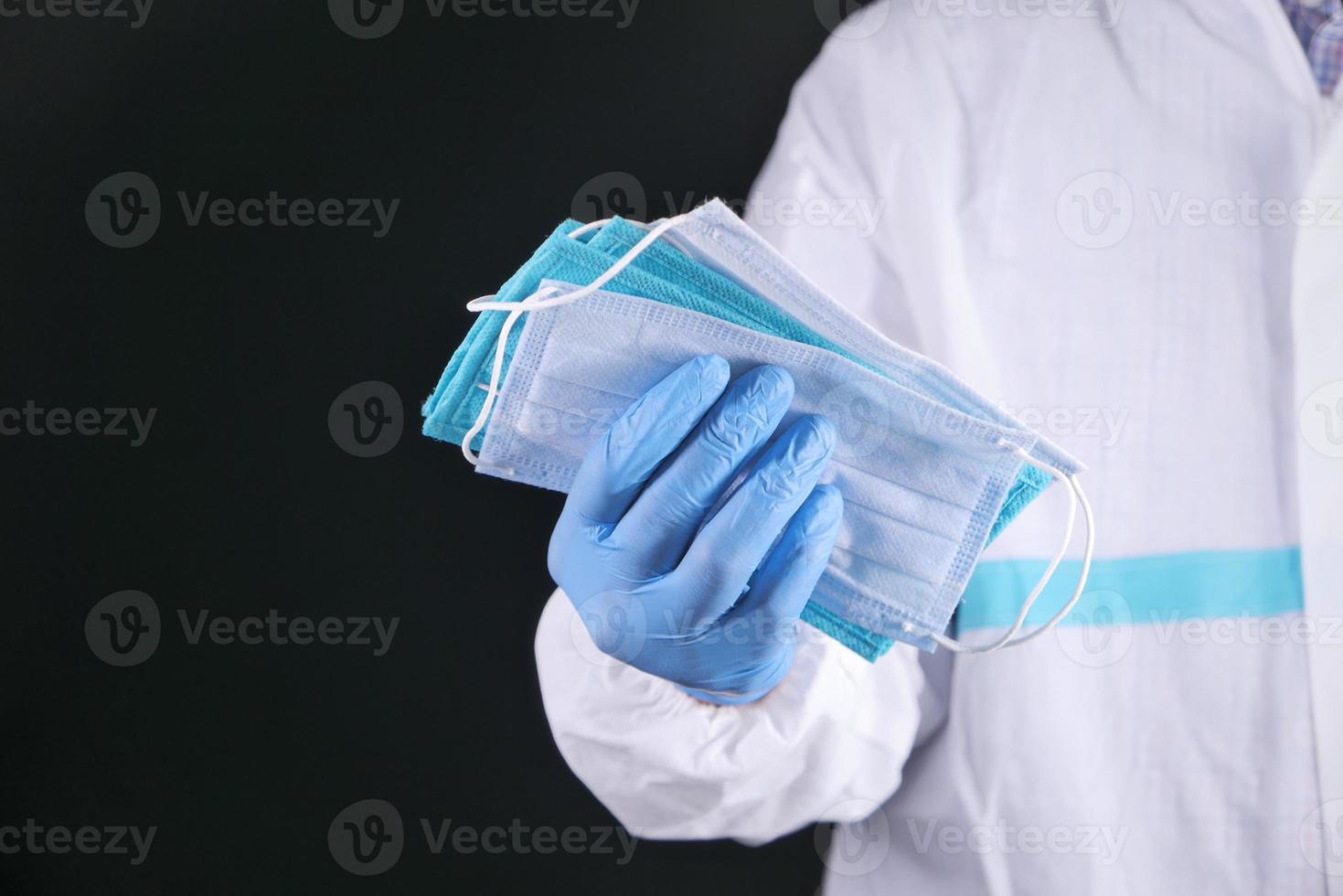 medizinischer Handschuh, der schützende chirurgische Gesichtsmasken hält foto