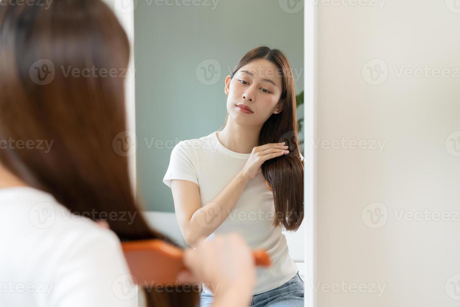 Gesundheit Haar Pflege, Schönheit bilden asiatisch Frau, Mädchen halten Haarbürste und Bürsten, Kämmen ihr lange Gerade Haar suchen beim Betrachtung im Spiegel im Morgen Routine nach Salon Behandlung, Frisur. foto