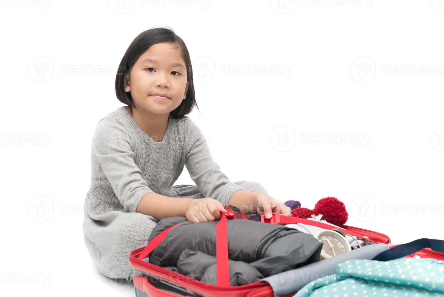 süß asiatisch Mädchen Verpackung Koffer vorbereiten zum Reise Ausflug isoliert foto