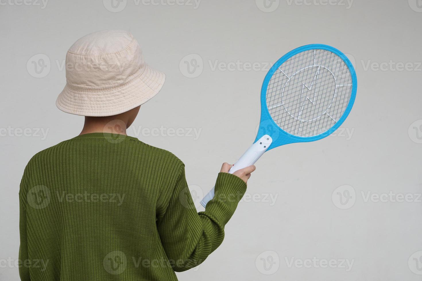 zurück Aussicht von Junge trägt Hut, hält Moskito elektrisch Fliegenklatsche Schläger. Konzept, elektrisch Gerät zu töten Mücken, Insekten, Fehler durch prügeln zu fliegend Insekten foto