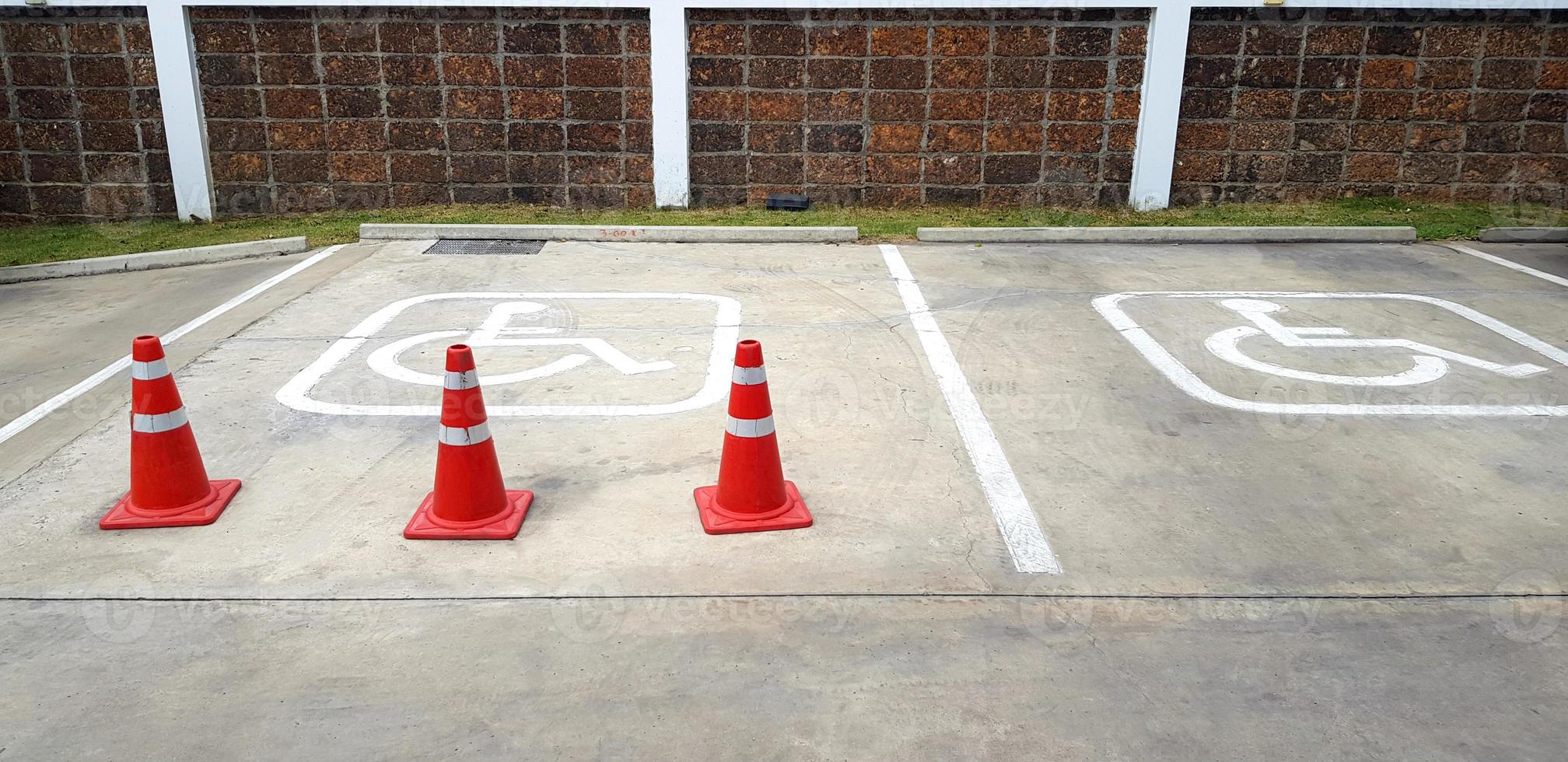 drei Orange der Verkehr Kegel auf Straße zum Reservierung Parkplatz von deaktiviert Menschen mit braun Backstein Mauer Hintergrund. Symbol, beschränken Bereich und Bedienung foto