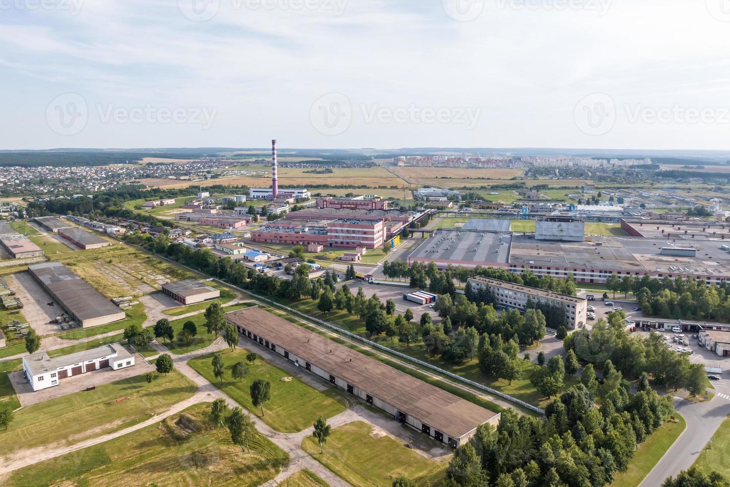 Antenne Panorama- Aussicht von Stadt mit ein enorm Fabrik mit Rauchen Schornsteine im das Hintergrund foto