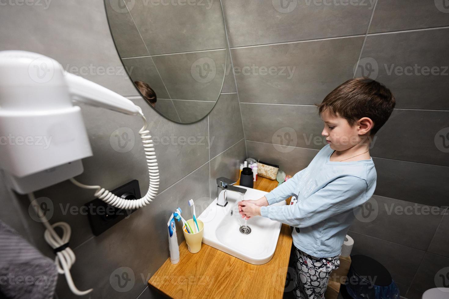 Junge wäscht Hände im das sinken beim Badezimmer. foto