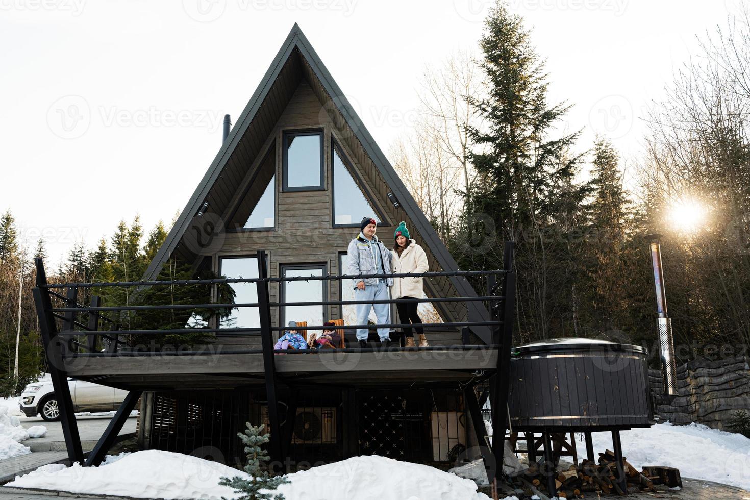 Familie mit zwei Töchter auf Terrasse aus Gitter winzig Haus im das Berge. foto