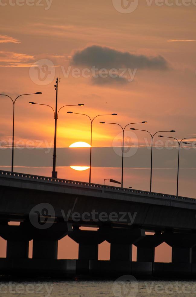 Hälfte von Sonne verschwinden im Wolke beim Brücke foto