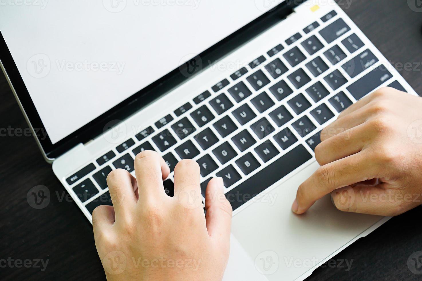 Männchen, das mit einem Laptop-Computer auf dem Tisch arbeitet foto
