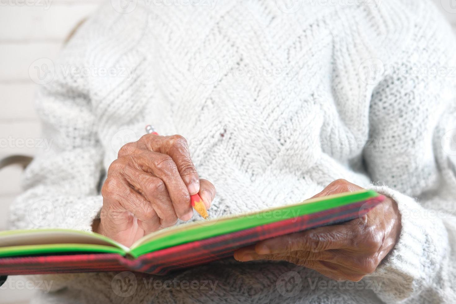 alte Frau, die in ein Notizbuch schreibt foto