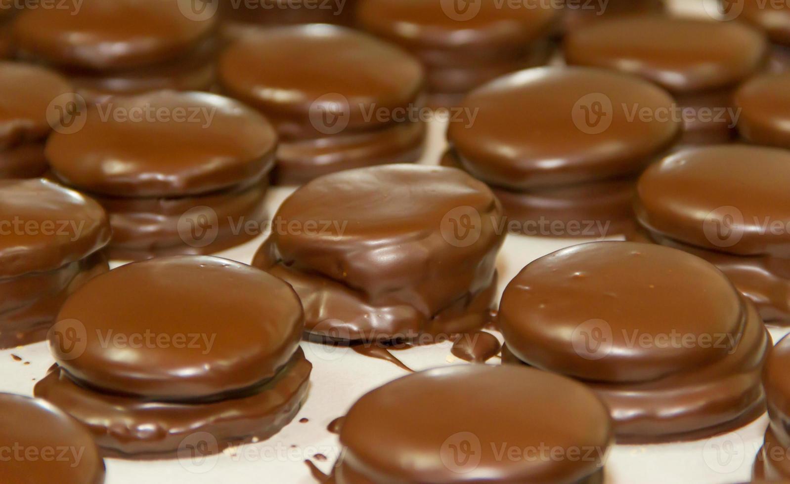 Vorbereitung von Alfajores von Dulce de leche gebadet im Schokolade foto