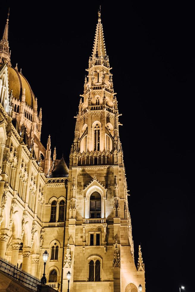 das ungarische parlament in budapest an der donau im nachtlicht der straßenlaternen foto