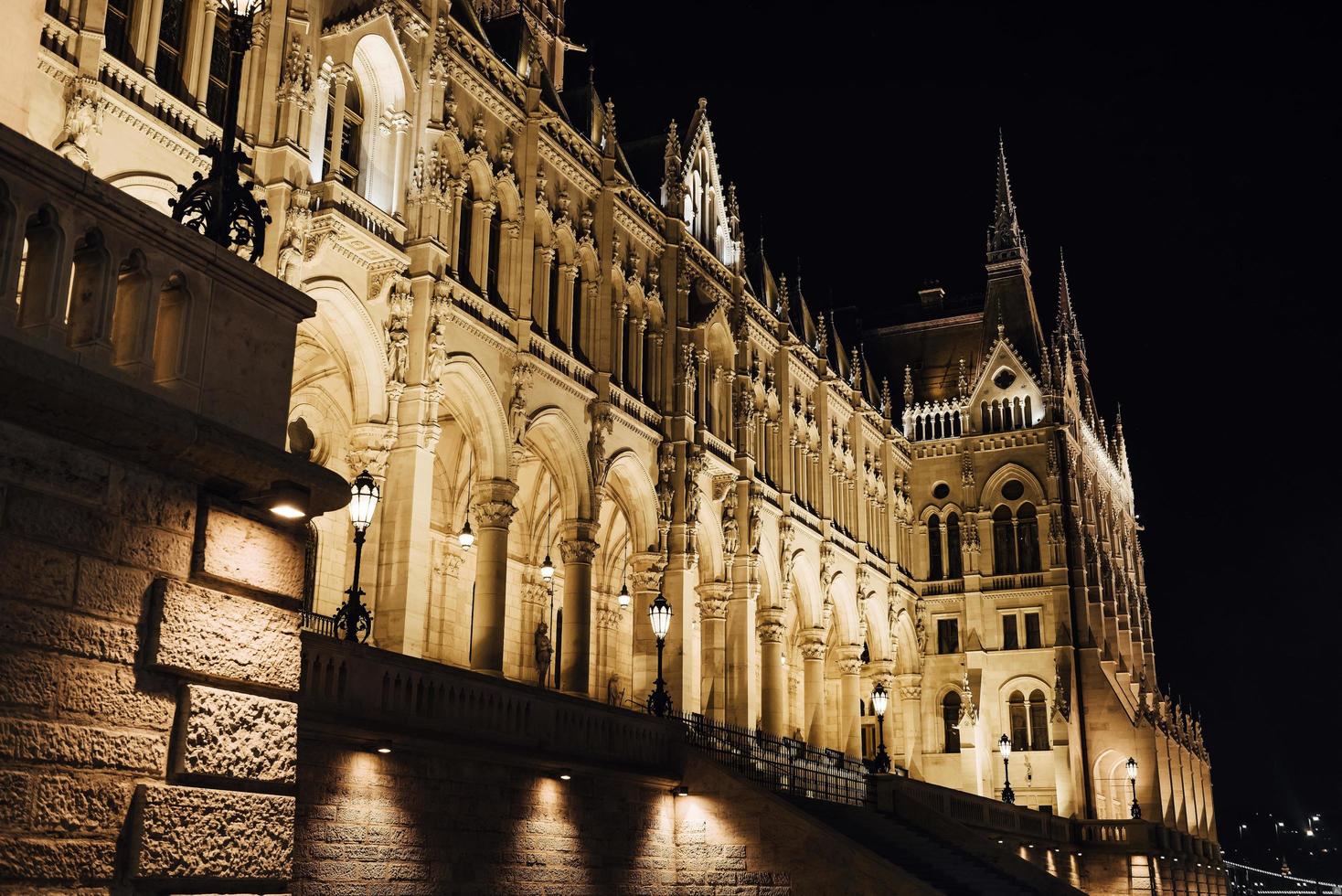 das ungarische parlament in budapest an der donau im nachtlicht der straßenlaternen foto