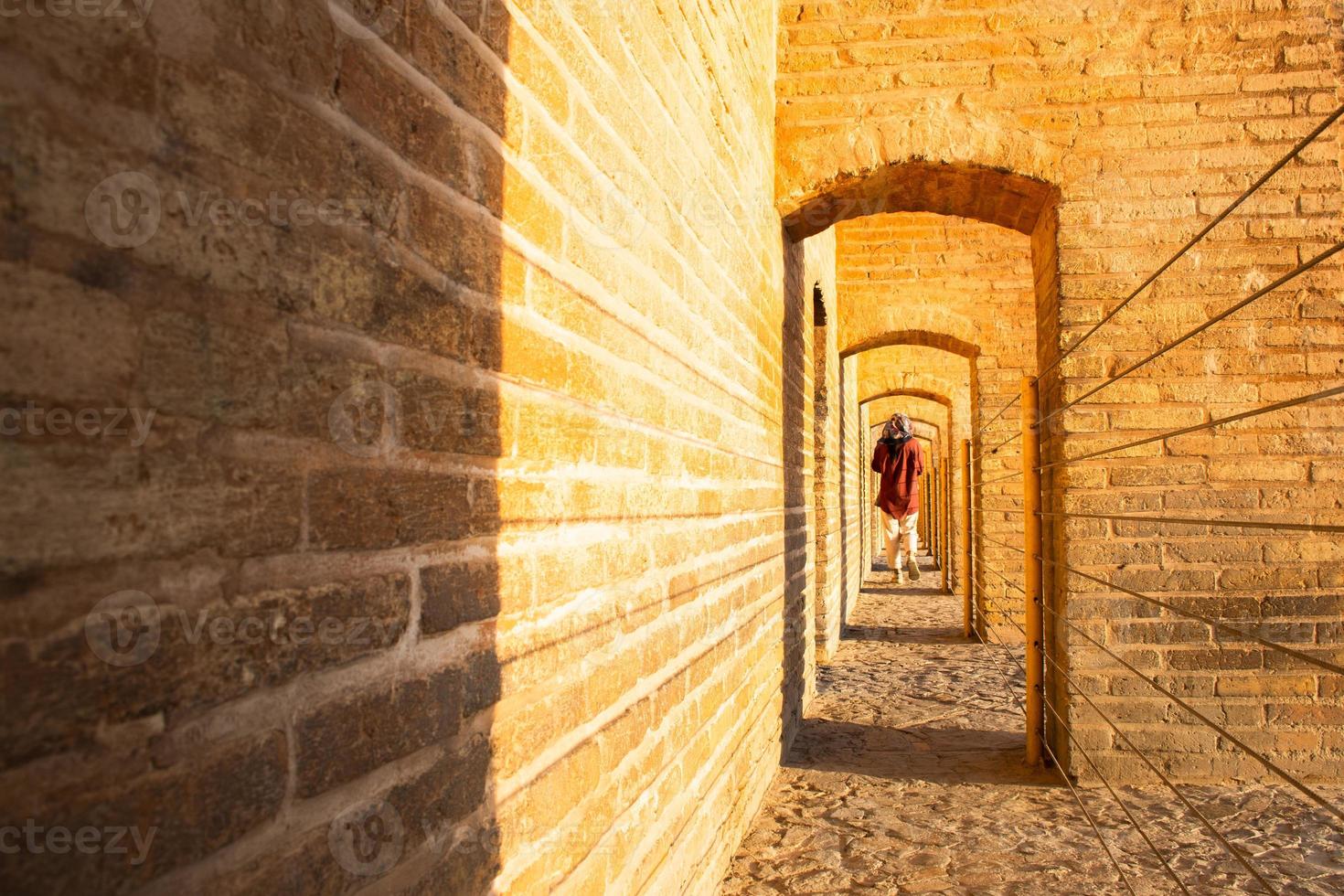 Isfahan, ich rannte ,2022 - - zurück Aussicht Frau gehen auf sio se pol oder Brücke von 33 Bögen, einer von das älteste Brücken von Esfahan und am längsten Brücke auf Zayandeh Fluss foto