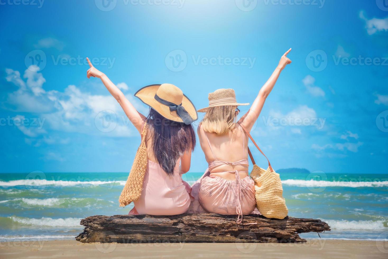 Porträt von zwei Frauen Sitzung und angehoben Waffen auf Sommer- tropisch Strand Ferien foto