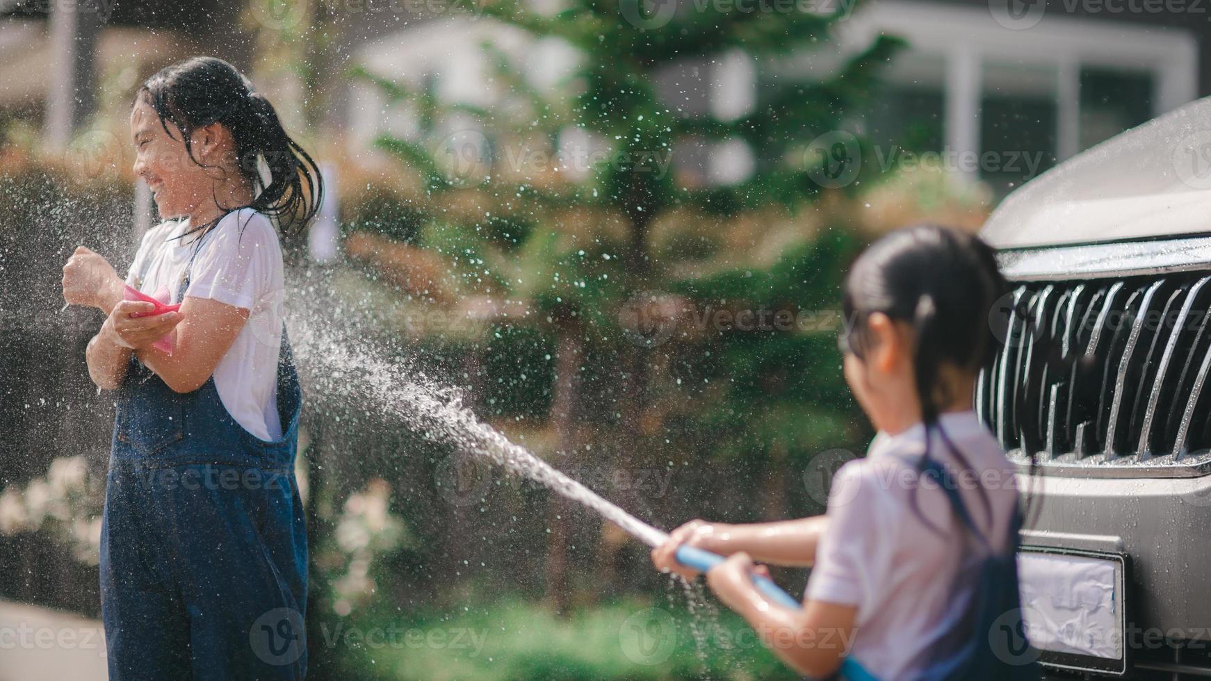 Geschwister asiatisch Mädchen waschen ihr Autos und haben Spaß spielen drinnen auf ein heiß Sommer- Tag. foto