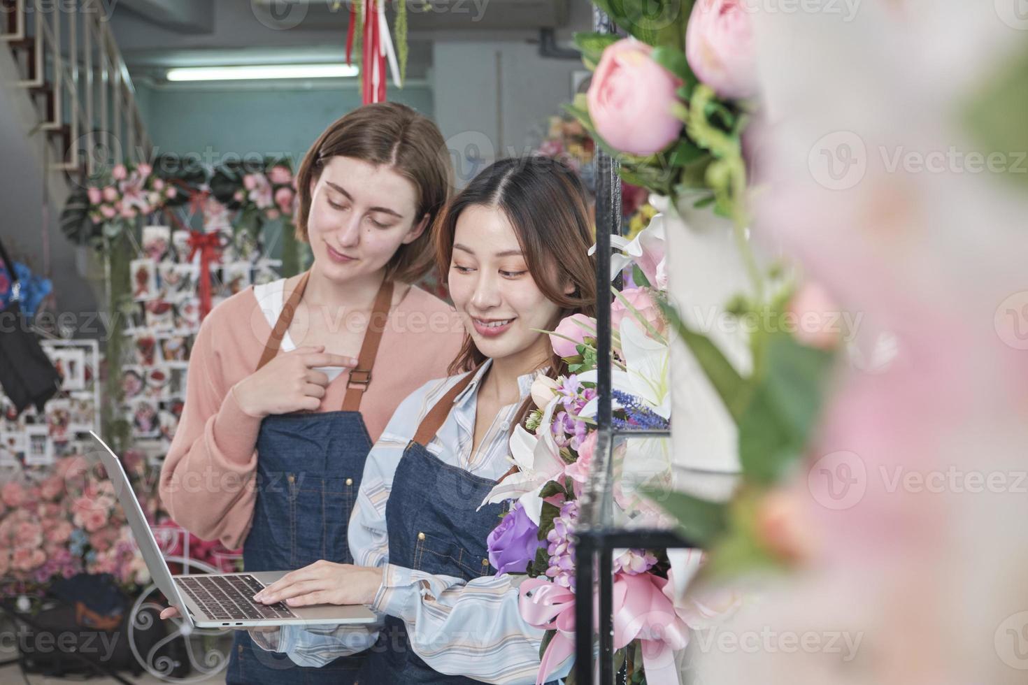 zwei jung schön weiblich Florist Partner schmücken schön Flora Bündel zum online Kauf Aufträge und Webseite Anordnung zum Geschäft, glücklich Arbeit im bunt Blume Geschäft speichern, und E-Commerce klein. foto