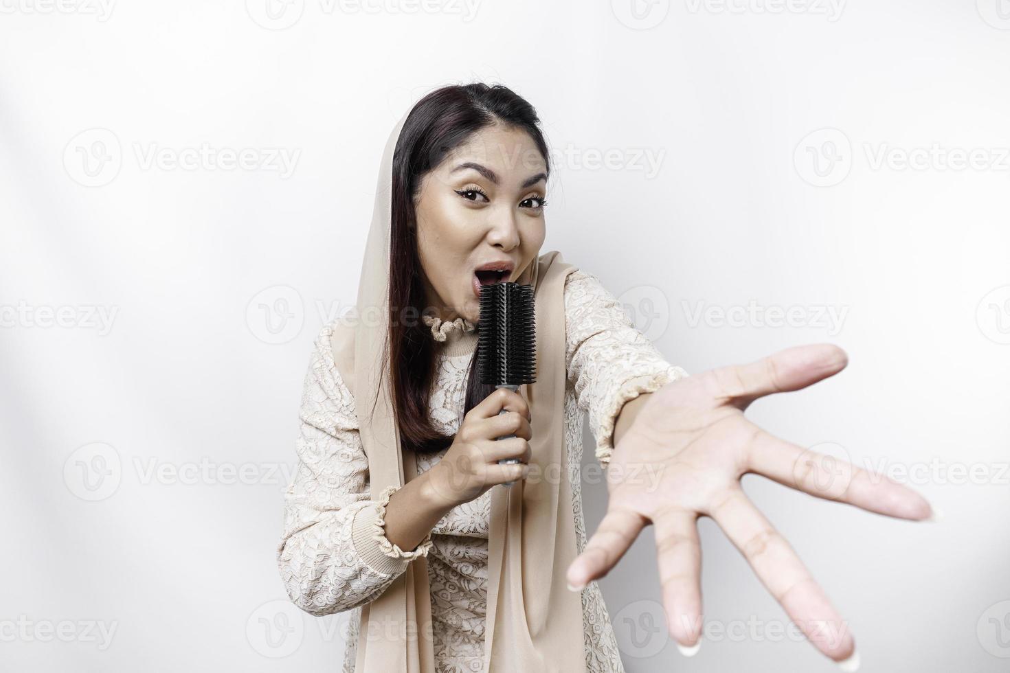 Porträt von sorglos asiatisch Muslim Frau, haben Spaß Karaoke, Singen im Mikrofon während Stehen Über Weiß Hintergrund foto