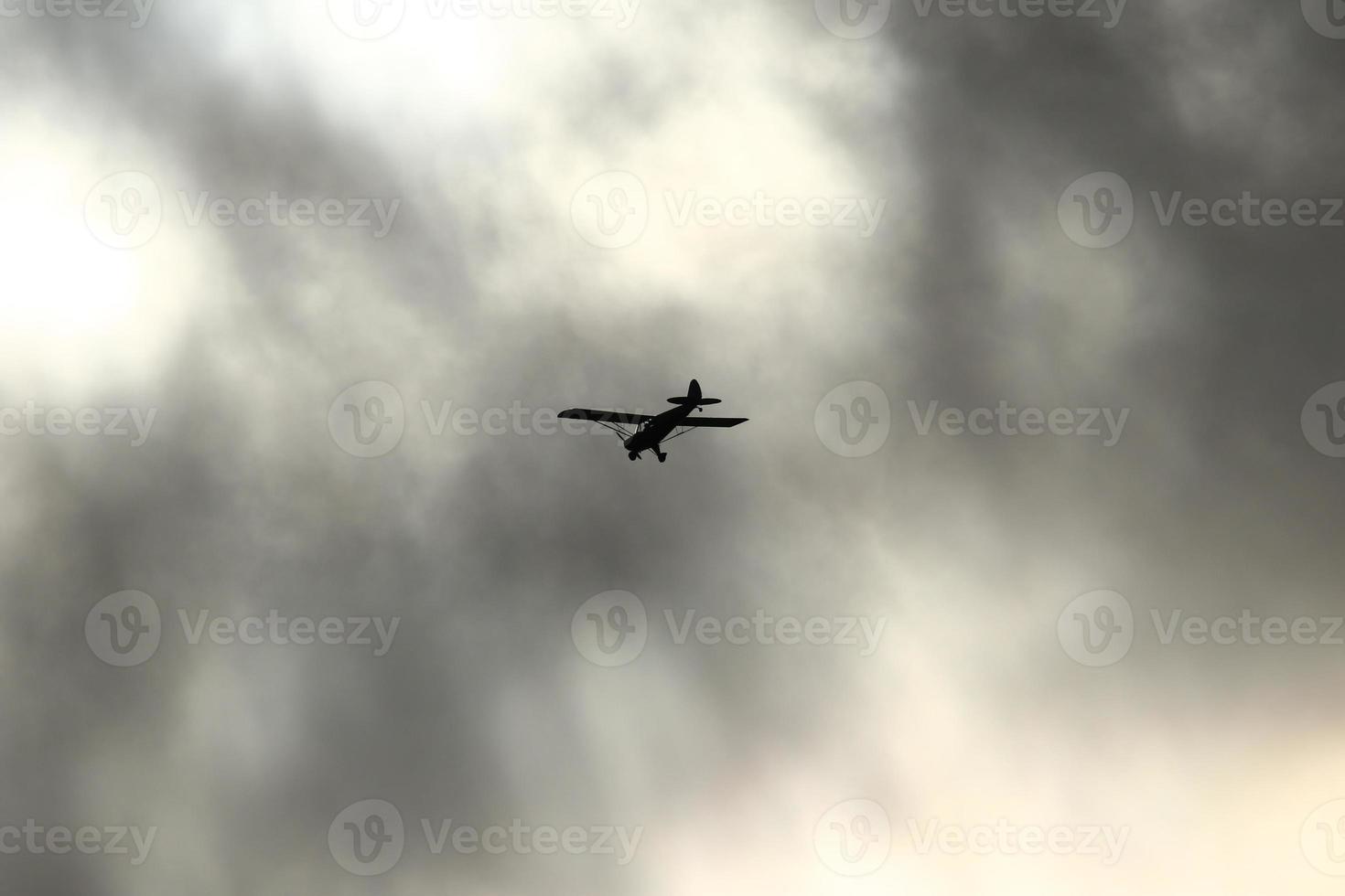 klein Flugzeug fliegend im das Himmel gegen dunkel Wolken foto