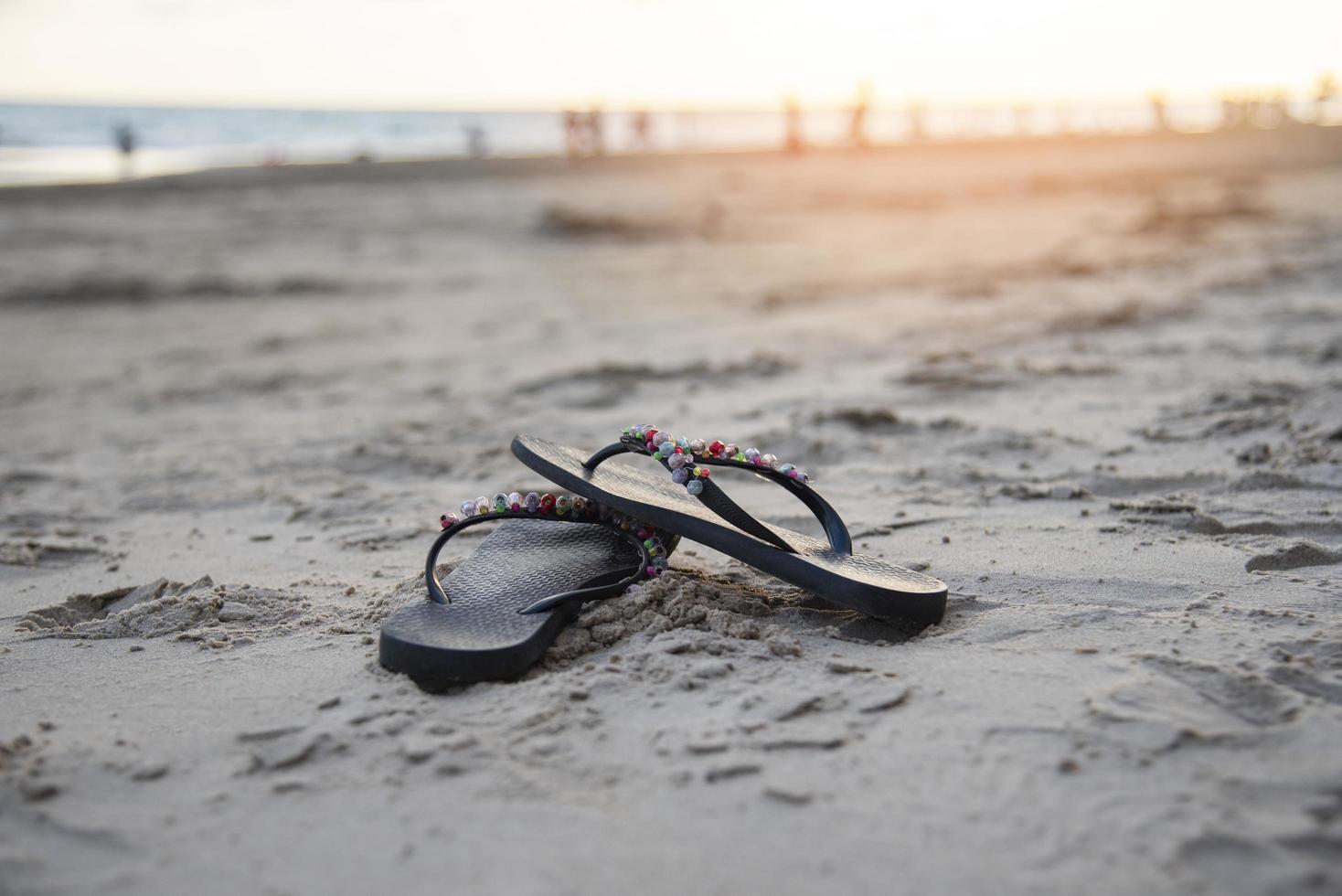 Flip Flops auf Strand mit sandig Strand Sonnenuntergang und Ozean Meer foto