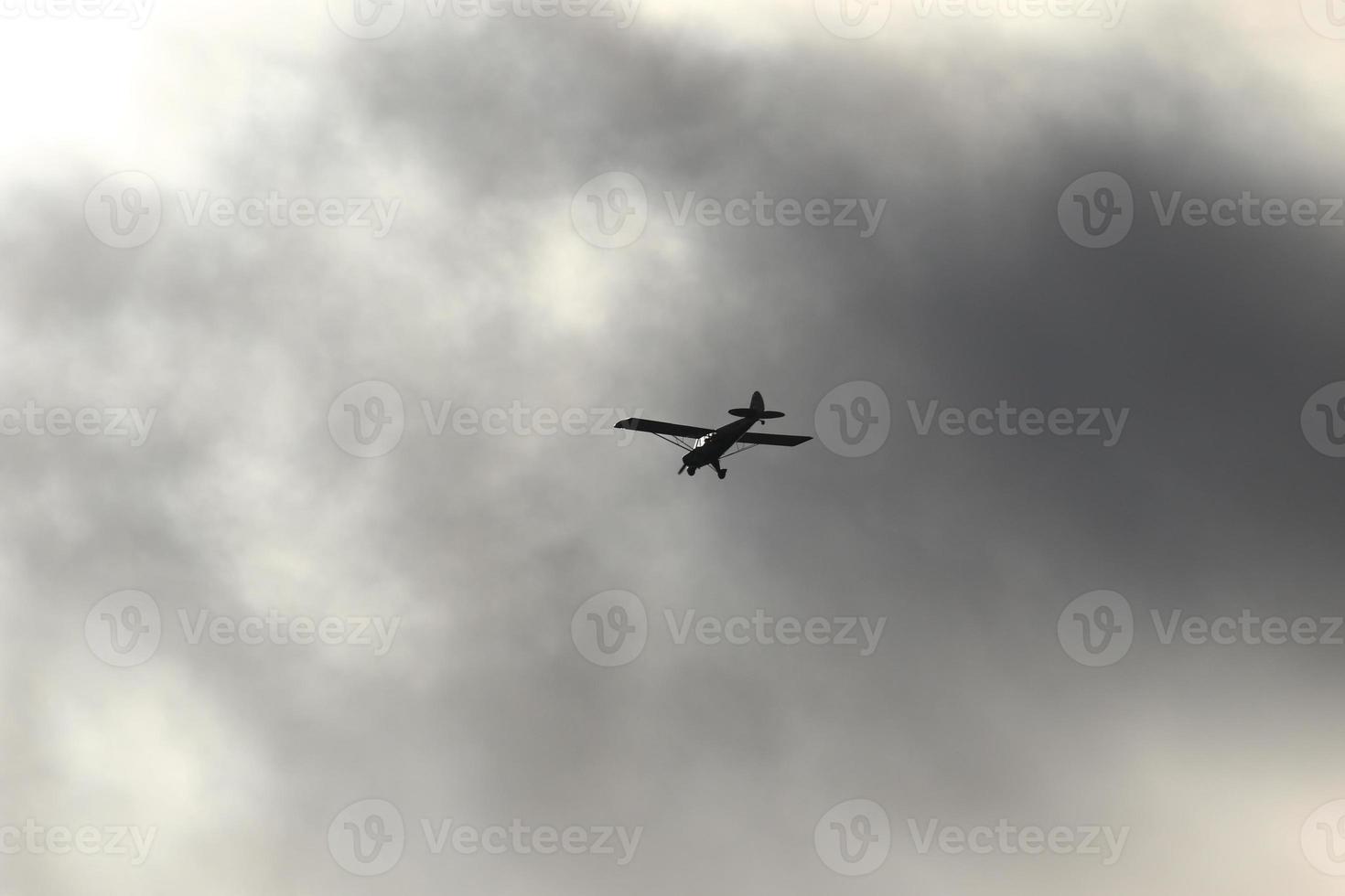 klein Flugzeug fliegend im das Himmel gegen dunkel Wolken foto