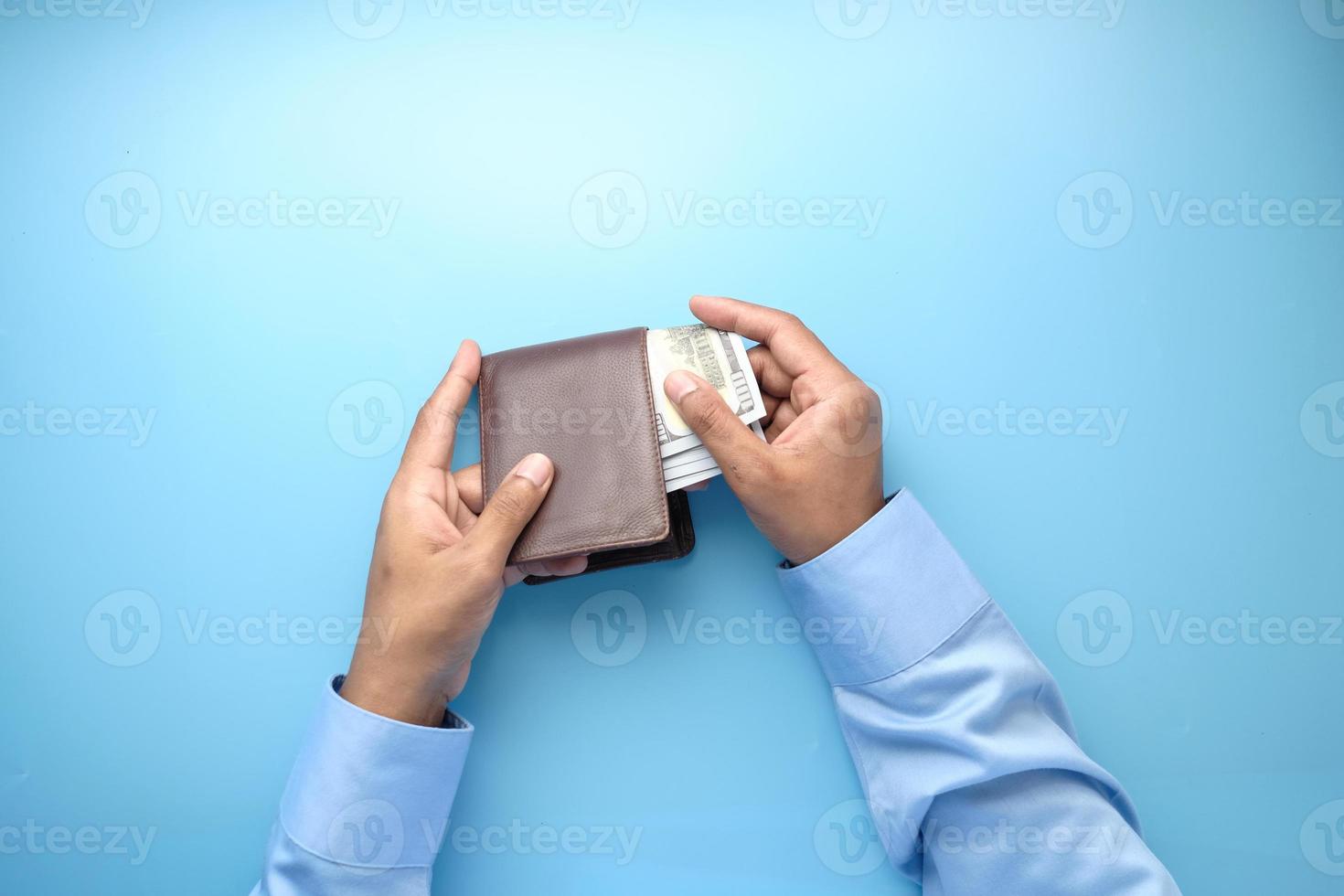 Bargeld aus der Brieftasche auf blauem Hintergrund herausnehmen foto