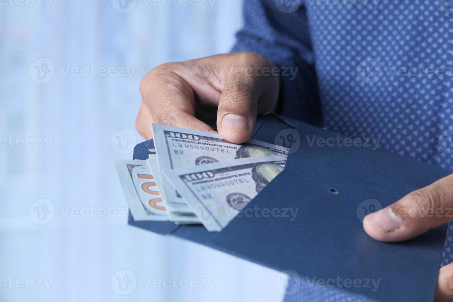 Hand der Person, die Bargeld in einen Umschlag steckt foto