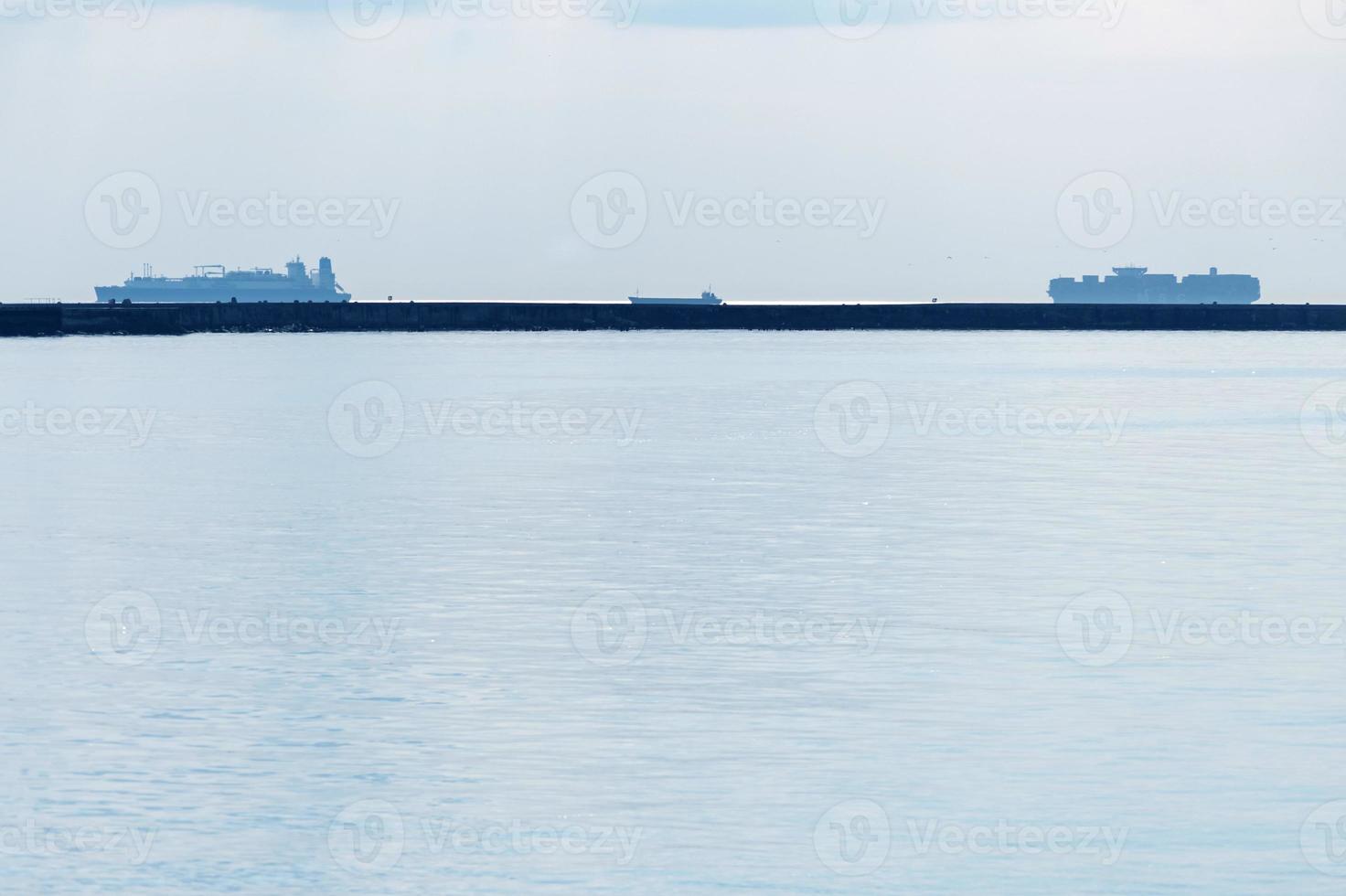 Meereslandschaft mit Frachtschiffen am Horizont. Küste in der Bucht. Schiffe befördern Frachtcontainer, Angeln und Parken. foto