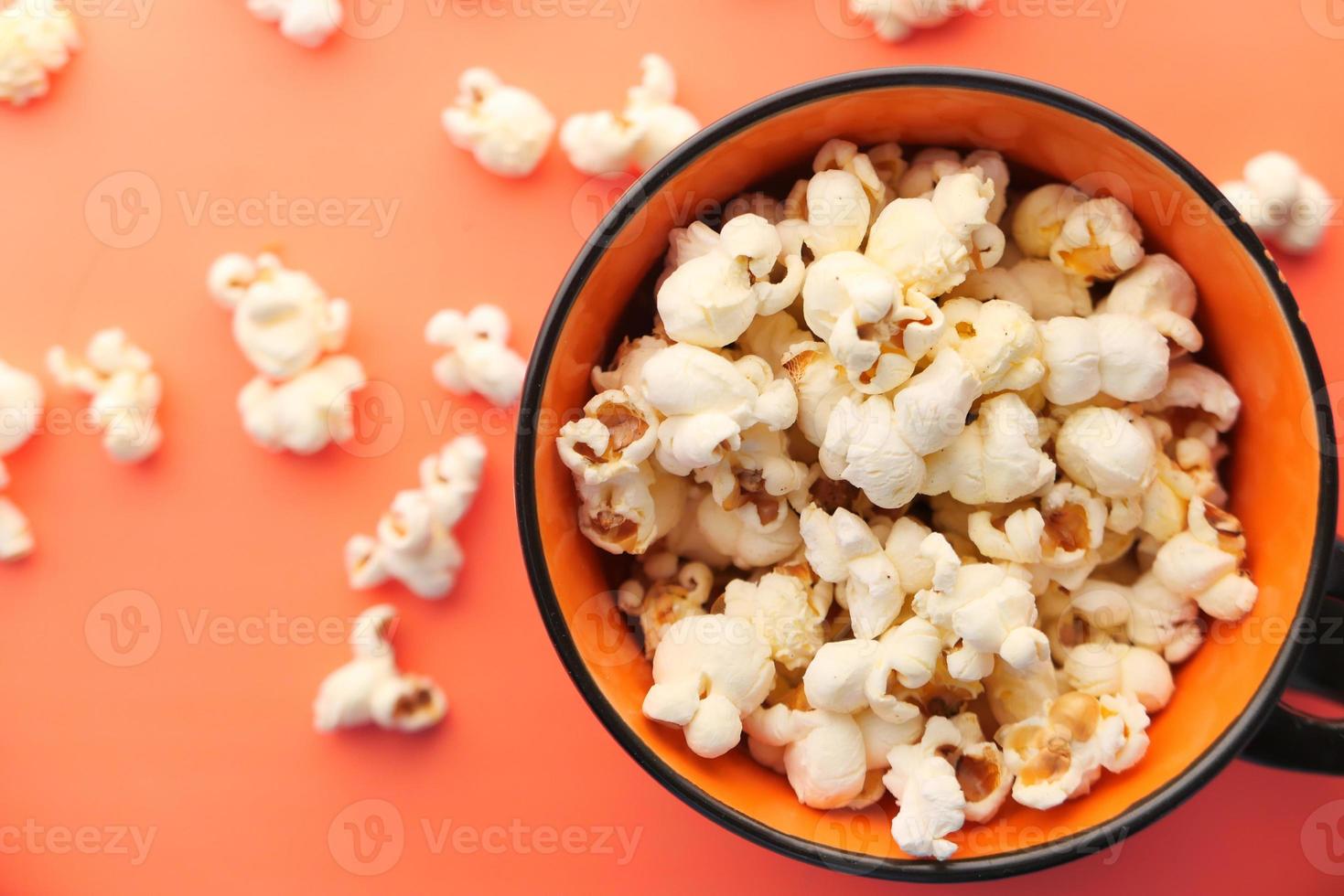 Popcorn in einer Schüssel auf orange Hintergrund Draufsicht foto