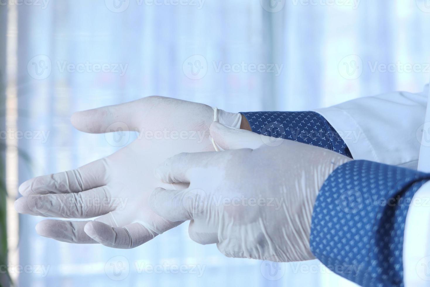 Mann zieht weiße medizinische Handschuhe an foto