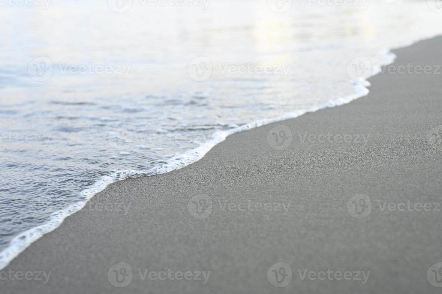 verschwommene Welle des Meeres am abendlichen Sandstrand foto