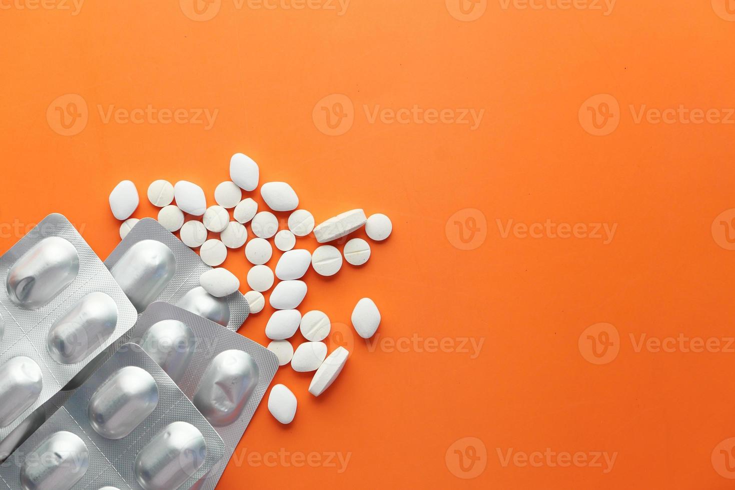 weiße Pillen und Blisterpackung auf orangefarbenem Hintergrund foto