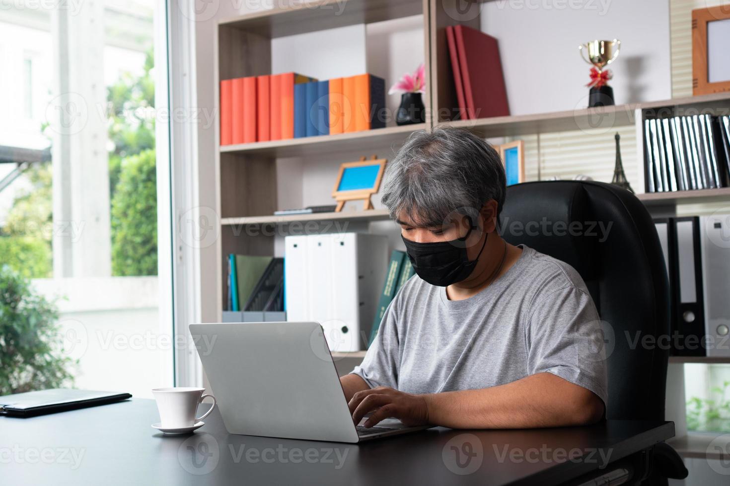 asiatisch Mann tragen Masken und Arbeiten von Zuhause während covid-19 Quarantäne, Konzept von Sozial Entfernung und Verhütung Sein weit verbreitet von Coronavirus oder covid 19 foto