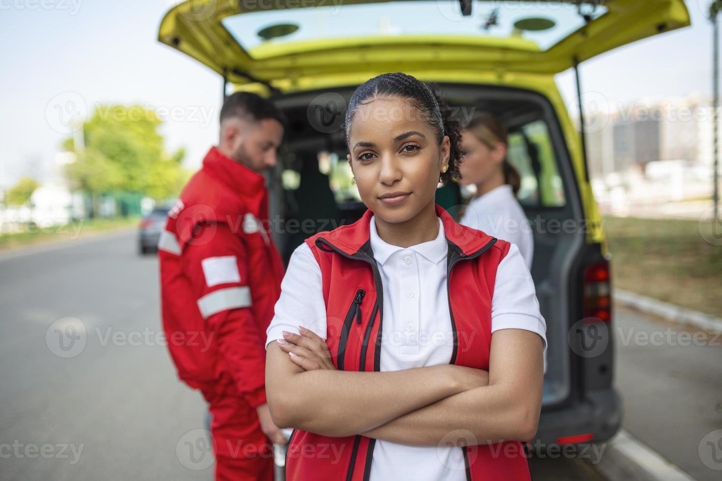 jung weiblich afrikanisch amerikanisch Sanitäter Stehen Rückseite von das Krankenwagen. Sanitäter durch das Krankenwagen. zwei Sanitäter nehmen aus Bahre von Krankenwagen foto