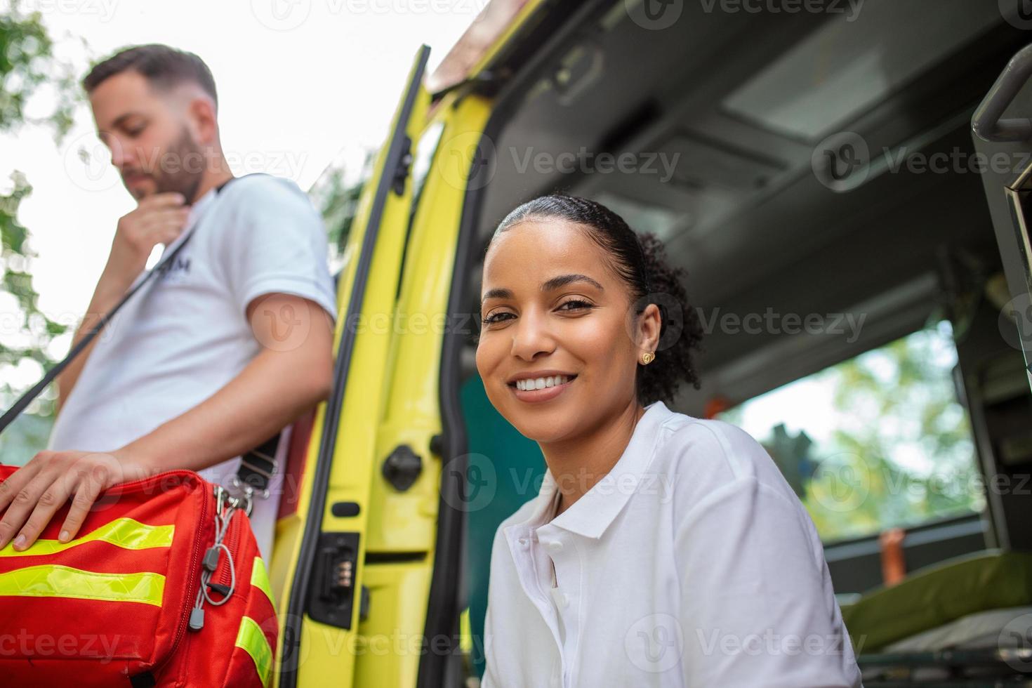 multiethnisch Sanitäter Stehen beim das ab von ein Krankenwagen. Notfall Arzt und Krankenschwester Stehen im Vorderseite von Krankenwagen foto