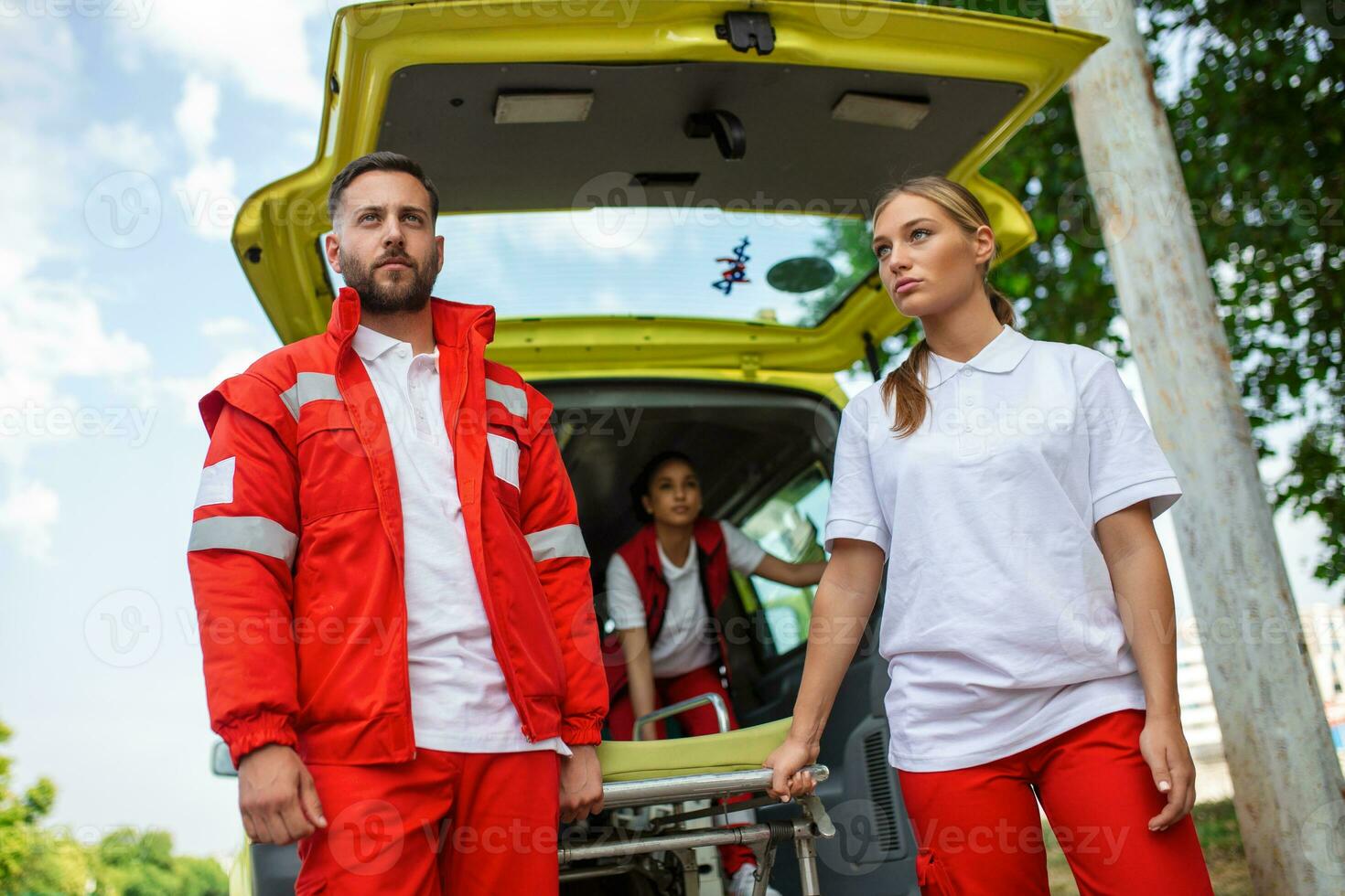 Sanitäter ziehen um aus Krankenwagen Bahre von Wagen. Sanitäter rollen das Krankenwagen Bahre foto