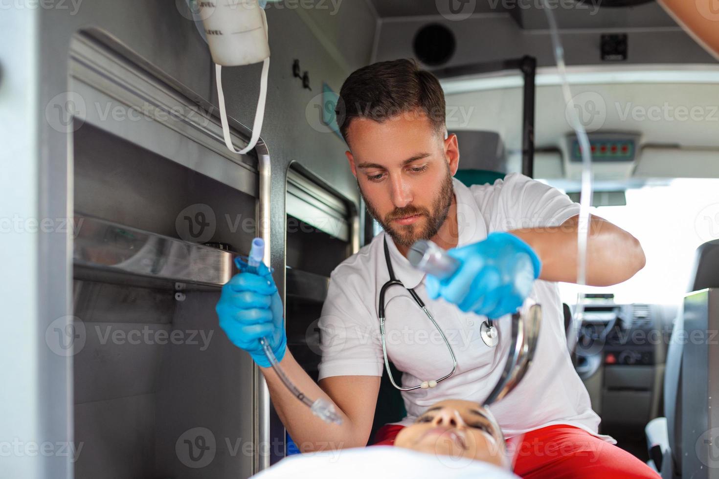 Arzt ist bereit zum endotracheal Intubation zum nicht Atmung geduldig. jung weiblich Sanitäter halten iv Lösung. ems Sanitäter zur Verfügung stellen medizinisch Hilfe zu ein verletzt geduldig auf das Weg zu ein Krankenhaus foto