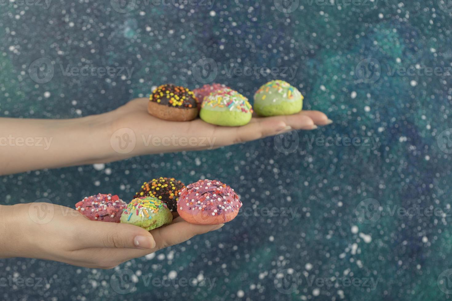 Hände halten bunte süße kleine Donuts mit Streuseln foto