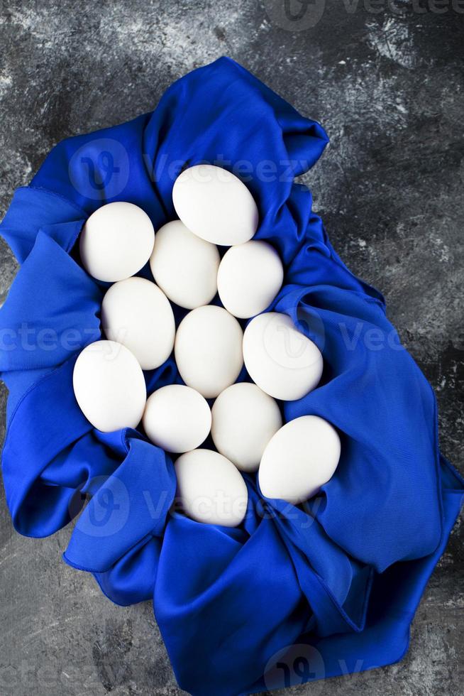 weiße rohe Hühnereier mit auf einer blauen Tischdecke foto