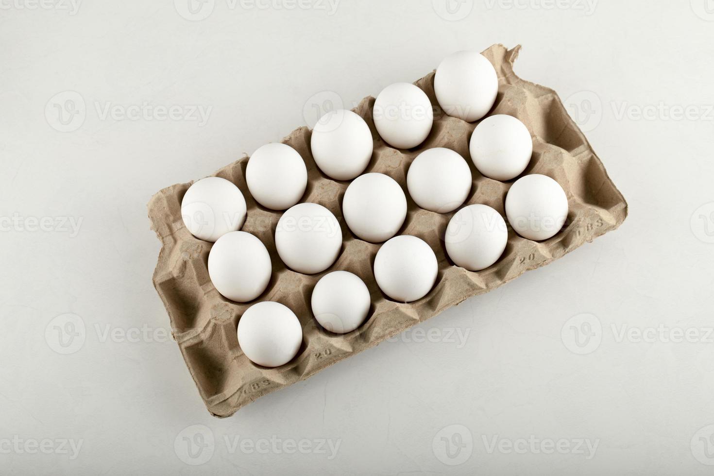 rohe Hühnereier in einer Eierbox auf einem weißen Hintergrund foto