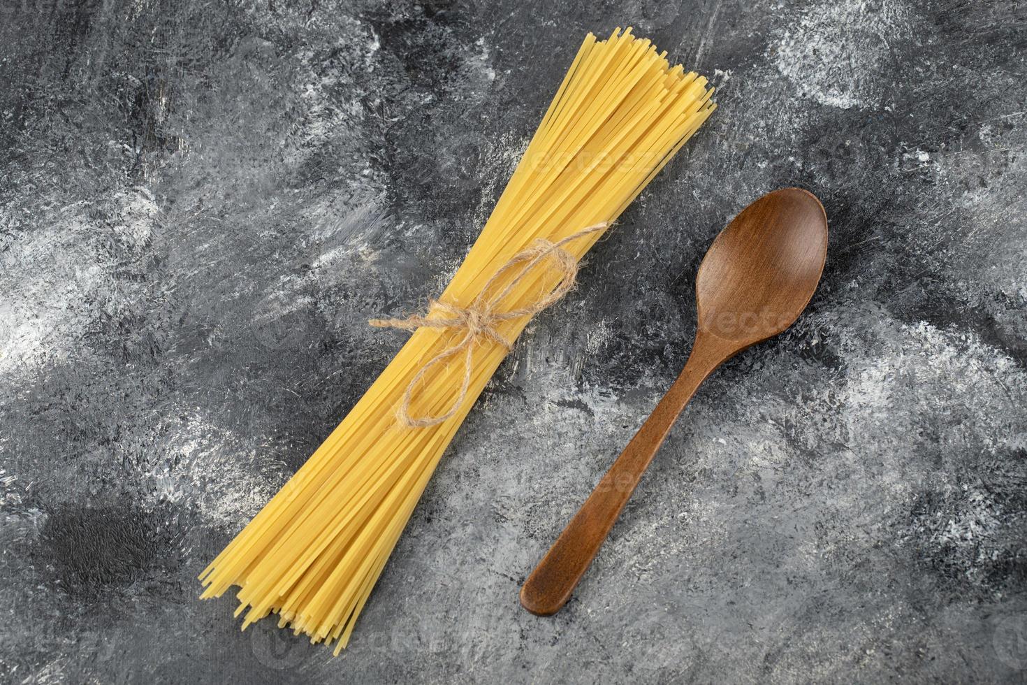 trockene Spaghetti und ein Holzlöffel auf einem Marmorhintergrund foto