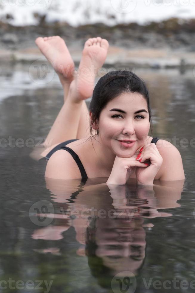 Plus Größe Modell- im schwarz Baden passen Lügen im geothermisch Mineral Wasser im Schwimmbad beim Balneotherapie Spa foto