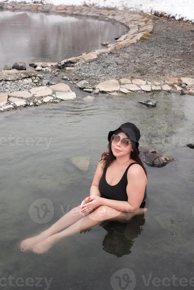 kurvig voll dachte Frau im schwarz ein Stück Baden Badeanzug Sitzung im draußen Schwimmbad beim Spa Resort foto