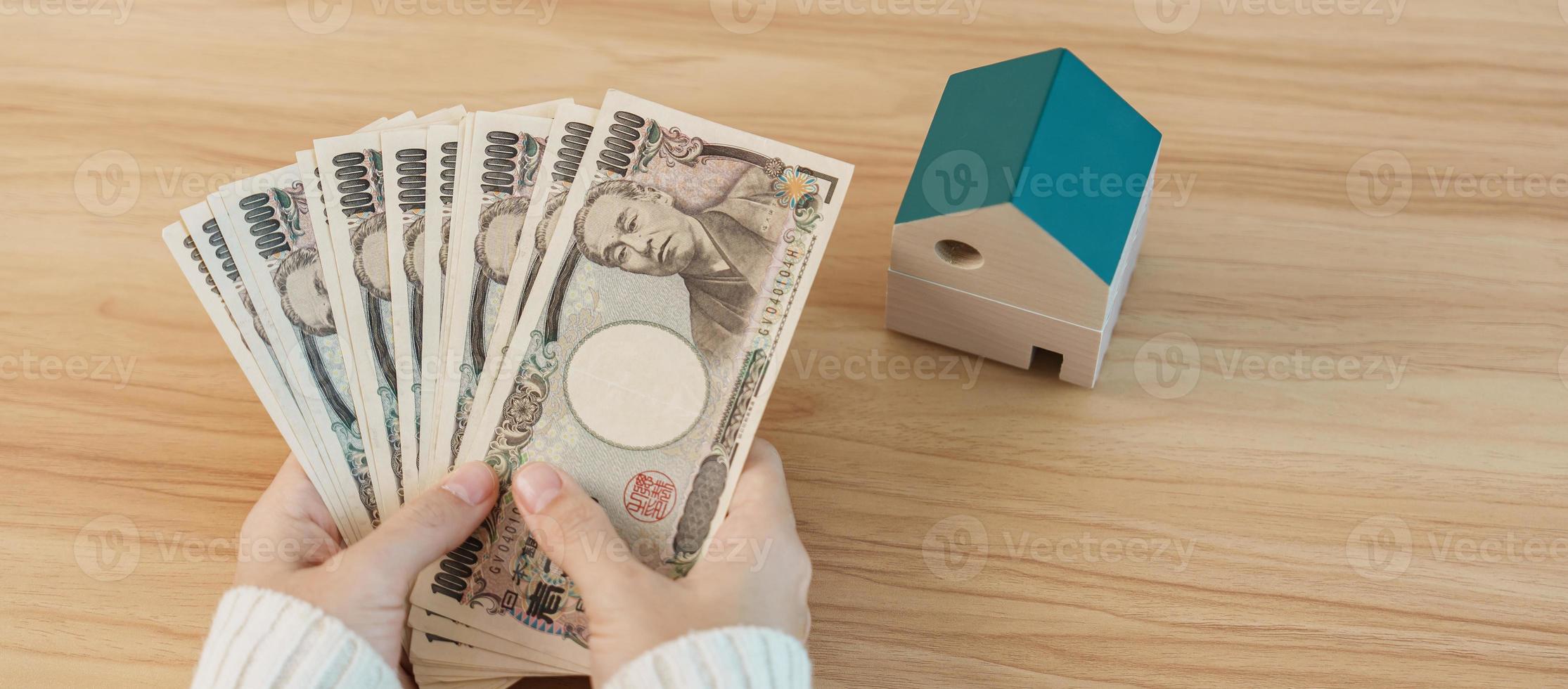 Frau mit japanischer Yen-Banknote und Hausmodell. immobilien, haus, hypothek, japanisches bargeld, steuer, rezessionswirtschaft, inflation, investition, finanz- und sparkonzepte foto