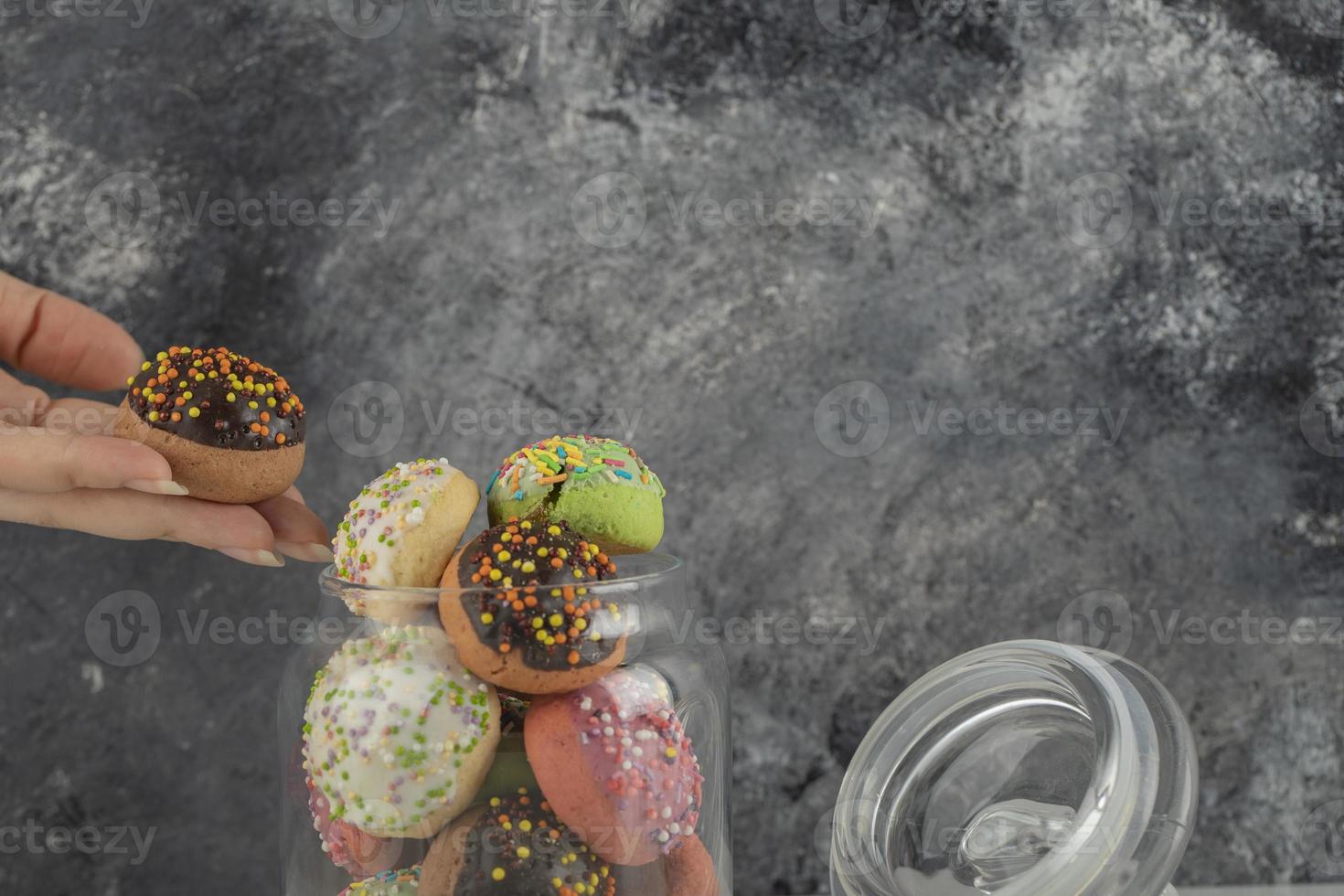 Frauenhand nimmt einen Donut aus einem Glas foto