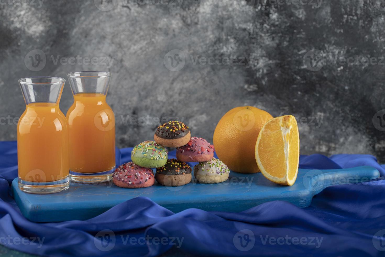 bunte süße Donuts mit Gläsern Saft und geschnittenen Früchten foto