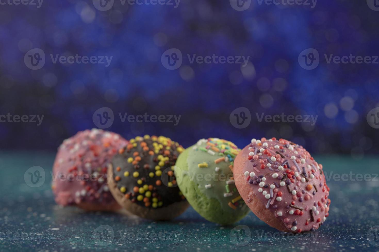 bunte kleine Donuts mit Streuseln auf blauem Hintergrund foto