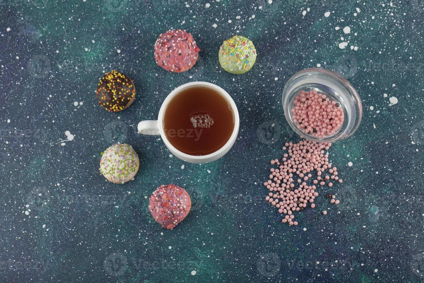 eine weiße Tasse Tee mit kleinen leckeren Donuts foto